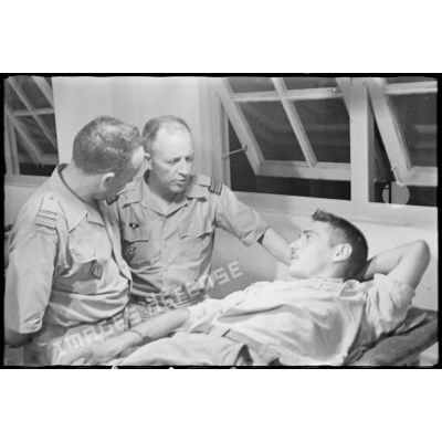 Dans la salle de triage de l'hôpital militaire Lanessan, le médecin-colonel Terramorsi, directeur du Service de santé au Nord-Vietnam et son ajoint, s'entretiennent avec un soldat, blessé dans la bataille de Diên Biên Phu.