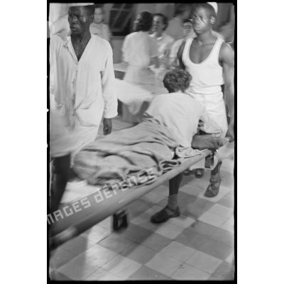 Un soldat, blessé dans la bataille de Diên Biên Phu, est transporté par des brancardiers de l'hôpital militaire Lanessan.