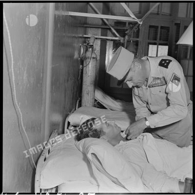 Le général Cogny, commandant en chef des FTNV (forces terrestres du Nord-Vietnam), décore un blessé rapatrié à l'hôpital militaire Lanessan.
