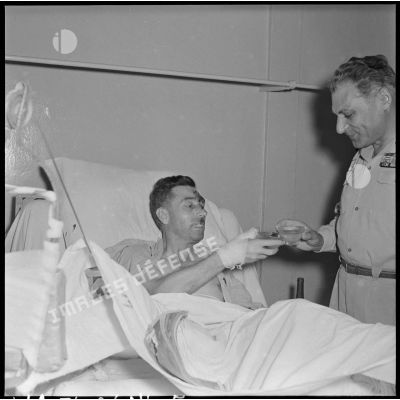 Le général Cogny, commandant en chef des FTNV (forces terrestres du Nord-Vietnam), trinque avec un capitaine blessé à Diên Biên Phu et rapatrié à l'hôpital militaire Lanessan.