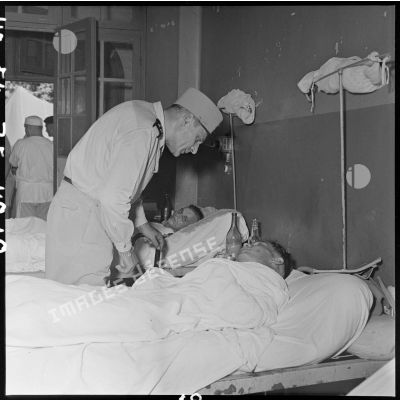 Le général Cogny, commandant en chef des FTNV (forces terrestres du Nord-Vietnam), au chevet d'un soldat blessé à Diên Biên Phu et soigné à l'hôpital militaire Lanessan d'Hanoï.