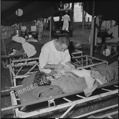 Les derniers blessés, évacués de Diên Biên Phu, reçoivent les premiers soins dans une tente de triage installée à l'hôpital militaire Lanessan.	
