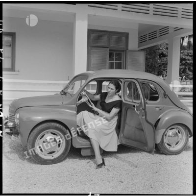 Une femme au volant d'une voiture dans un jardin du cantonnement des PFAT (personnel féminin de l'armée de Terre).