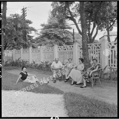 Groupe de femmes accompagnées d'un homme dans un jardin du cantonnement des PFAT (personnel féminin de l'armée de Terre).