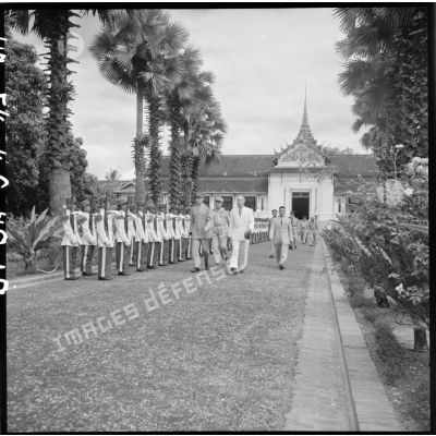 Les autorités civiles et militaires, françaises et laotiennes, quittent le palais du roi à Luang Prabang en passant devant la garde d'honneur.