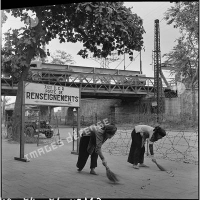 Femmes balayant un trottoir aux abords du poste de renseignements de la 71 CCR (compagnie de circulation routière).