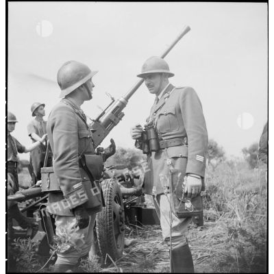 Lors d'une école à feu du 411e RAAA  (régiment d'artillerie antiaérienne) de la DMC (division de marche de Constantine), un capitaine et un lieutenant discutent devant un canon de 40 mm Bofors.