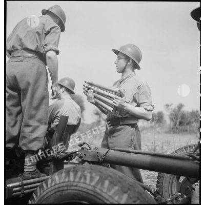 Lors d'une école à feu du 411e RAAA  (régiment d'artillerie antiaérienne) de la DMC (division de marche de Constantine), des artilleurs chargent un canon de 40 mm Bofors.