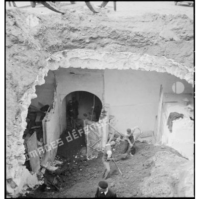 Des civils déblaient les gravats d'un cratère causé par l'explosion d'une bombe sur le boulevard de la République à Alger lors du bombardement allemand de la nuit du 18 au 19 avril 1943.