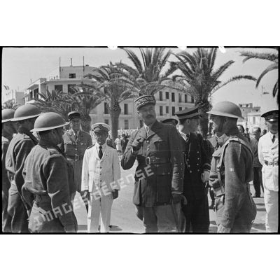 Au cours d'une cérémonie, le général d'armée Henri Giraud, commandant en chef civil et militaire, s'entretient et félicite des soldats du CFA (Corps franc d'Afrique), en présence du commandant Durand, commandant la 1re demi-brigade du CFA qui a participé à la prise de la ville de Bizerte.