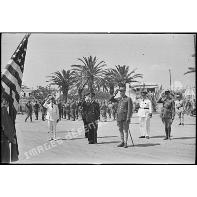 Le général d'armée Henri Giraud, commandant en chef civil et militaire, et le vice-amiral Marcel Leclerc, commandant la Marine en Tunisie, saluent le drapeau des Etats-Unis lors d'une cérémonie et d'un défilé des troupes.