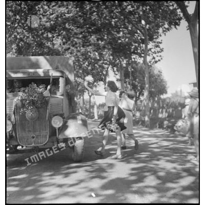 Des jeunes filles lancent des fleurs sur un camion Renault du 65e RAA (régiment d'artillerie d'Afrique), de retour à Blida après avoir participé à la campagne de Tunisie.