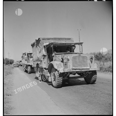 Une colonne de véhicules du 65e RAA (régiment d'artillerie d'Afrique), de retour de la campagne de Tunisie, circule sur une route menant à Blida. Au premier plan, un véhicule d'origine britannique.