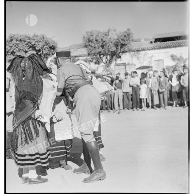 De retour de la campagne de Tunisie, le colonel Dumas, commandant le 65e RAA (régiment d'artillerie d'Afrique), embrassent des jeunes filles portant les costumes traditionnels alscien et lorrain.