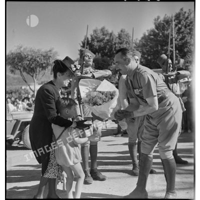 De retour de la campagne de Tunisie, le colonel Dumas, commandant le 65e RAA (régiment d'artillerie d'Afrique), reçoit des fleurs d'un jeune garçon à Blida.