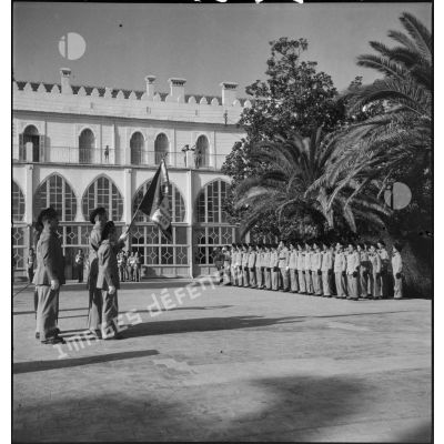 Présentation du drapeau de l'EMPNA (Ecole militaire préparatoire nord-africaine) aux enfants de troupes rassemblés dans la cour de l'école.