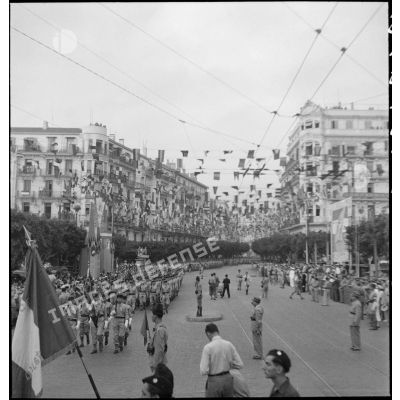 Défilé de la garde mobile lors du 14 juillet 1943 dans une rue pavoisée d'Alger.