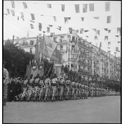 Défilé de tirailleurs du 19e RTS (régiment de tirailleurs sénégalais) (sous réserves), unité en garnison à Alger lors du 14 juillet 1943. Ils portent la tenue française avec écusson tricolore frappé de l'ancre de marine sur la poitrine.