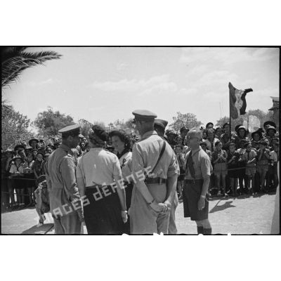 Lors d'une visite en Tunisie, le roi George VI, souverain britannique, félicite une éclaireuse du mouvement scout qui a fait évader des soldats britanniques pendant l'occupation allemande de Tunis.