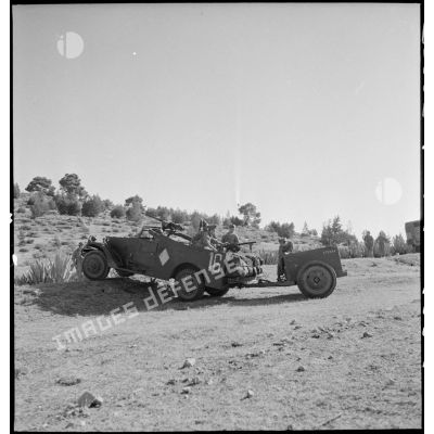 Scout-car M3A1 du 3e Régiment de spahis algériens de reconnaissance (RSAR) à l'entraînement, tractant une remorque blindée M8 au cours d'une manoeuvre du corps expéditionnaire français (CEF) dans le Sud algérien.