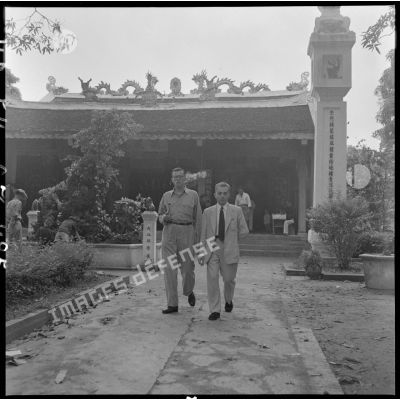 M. Jean Daridan (à gauche), commissaire général adjoint en Indochine, accompagné d'un civil, marche devant un temple.