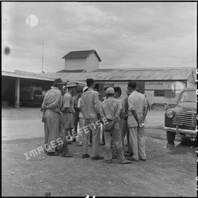 Groupe d'hommes, en pleine conversation, sur un parking de la base aérienne de Gia Lam.