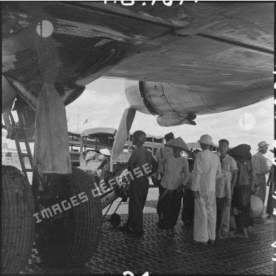 Civils nord-vietnamiens attendant sous l'aile d'un avion Dakota du pont aérien Hanoï-Saigon.