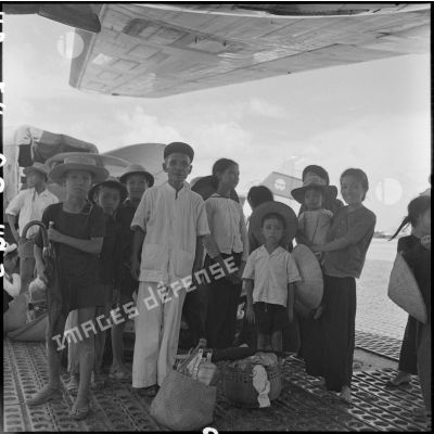 Groupe de civils sur le tarmac d'un aérodrome lors de l'évacuation de la population du Nord-Vietnam par le pont aérien Hanoï-Saigon.