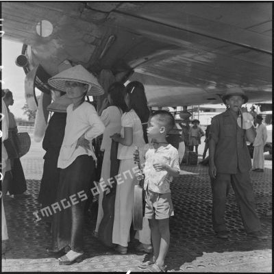 Femmes et enfant devant la soute d'un avion affrété pour l'évacuation de la population du Nord-Vietnam.	