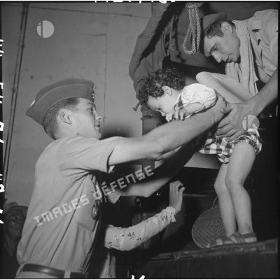 Des militaires du CEFEO (Corps expéditionnaire français en Extrême-Orient ) aident un enfant réfugié à descendre d'un camion.