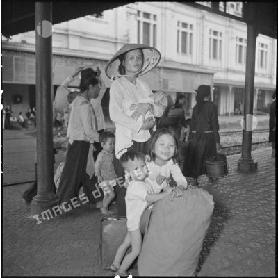 Une femme et de jeunes enfants sur un quai de la gare d'Hanoï.