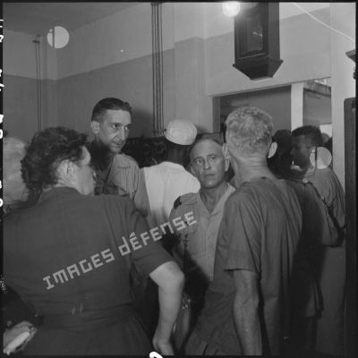 Lors d'une visite médicale organisée au retour des officiers supérieurs prisonniers à Diên Biên Phu, un prisonnier de guerre discute avec des officiers et deux femmes.