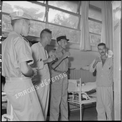 Le colonel Lalande en visite à l'hôpital militaire Lanessan, partage un verre avec trois hommes.