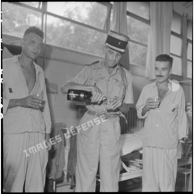 Le colonel Lalande (au centre), en visite à l'hôpital militaire Lanessan, partage un verre avec deux militaires hospitalisés.