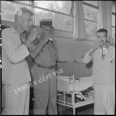 Le colonel Lalande (au centre) en visite à l'hôpital militaire Lanessan, partage un verre avec deux militaires hospitalisés.