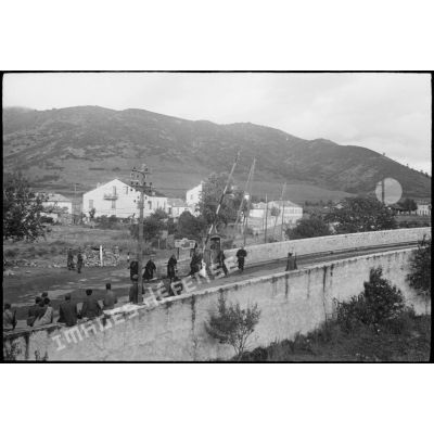 Sous le contrôle de soldats italiens, des goumiers franchissent un point de contrôle gardant l'accès d'une route et d'un pont, menant probablement à Saint-Florent (intersection des N 197 et N 193, dans la commune de Ponte-Leccia).