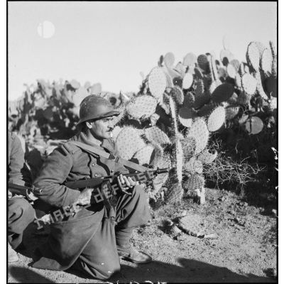 Tirailleur du 9e RTA (régiment de tirailleurs algériens) de la DMC (Division de marche de Constantine) armé d'un pistolet-mitrailleur Thompson M1 avec chargeur circulaire, posté au milieu de cactus.