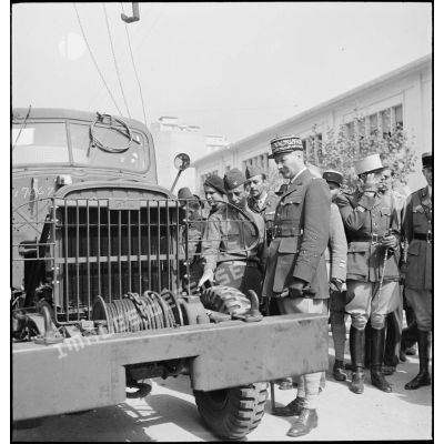 Dans le cadre du réarmement de l'armée française par les Etats-Unis, sur une chaîne de montage sur le port d'Alger, un colonel de l'armée de l'air américaine présente un camion de transport GMC au général d'armée Henri Giraud, commandant en chef civil et militaire.