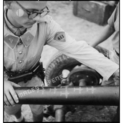 Un élève aspirant du 411e groupement d’artillerie de DCA-DAT (défense contre les aéronefs - défense aérienne du territoire) examine le fût d'un canon de 40 mm Bofors sur lequel figurent des silhouettes d'avions symbolisant le tableau de chasse de la pièce d'artillerie.