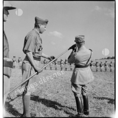 Au cours d'une prise d'armes, le général de corps d'armée Louis Koeltz, commandant le 19e CA (corps d'armée), décore de la Croix de guerre le fanion d'un escadron du 5e RCA (régiment de chasseurs d'Afrique) que lui présente son commandant.