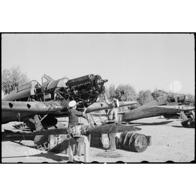 Deux mécaniciens de l'armée de l'Air française démontent le moteur d'un avion de chasse Hawker Hurricane sur une chaîne de maintenance.