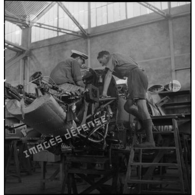 Deux mécaniciens vérifient le moteur d'un chasseur Supermarine Spitfire sur une chaîne de maintenance de l'armée de l'Air.