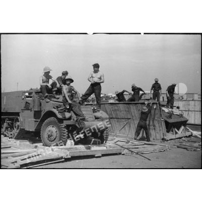 Une automitrailleuse M8 (ou light armored car) et un half-track M3 sont sortis de leur caisse de transport par des équipes de montage sur le port de Casablanca.