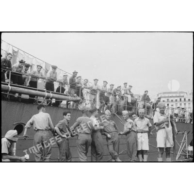 Des tirailleurs du 1er régiment de tirailleurs marocains (RTM) et des marins patientent sur un quai du port d'Alger avant l'appareillage de navires pour la Corse.