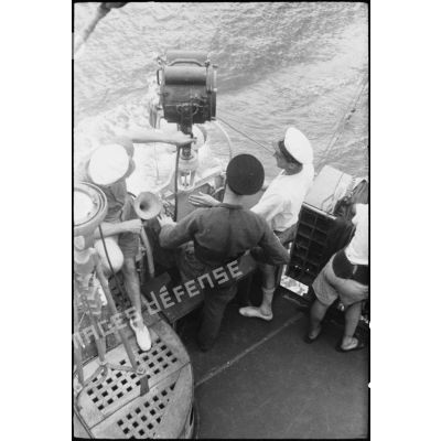 Marins à leur poste d'observation sur la passerelle extérieure d'un des bâtiments du convoi. A gauche, une lanterne Scott et une alidade de navigation.