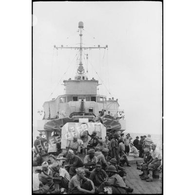 Des tirailleurs du 1er régiment de tirailleurs marocains (RTM) sont rassemblés sur le pont  avant d'un navire à destination de la Corse.