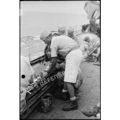 Des tirailleurs du 1er RTM (régiment de tirailleurs marocains) se restaurent sur le pont d'un torpilleur ou contre-torpilleur naviguant vers la Corse.