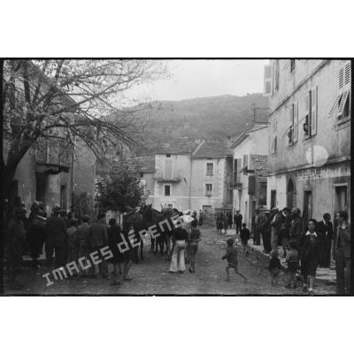 Des soldats français et italiens se trouvent dans une rue de la commune, au milieu de la population civile.