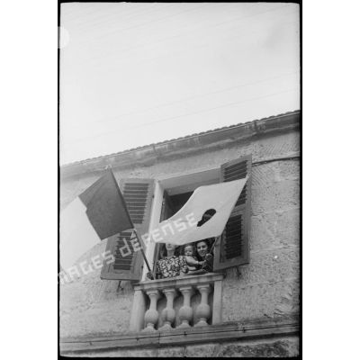 Des femmes pavoisent, avec les drapeaux français et corse, la fenêtre d'une maison de la commune de Saint-Florent qui vient d'être libérée.