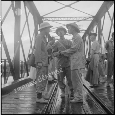 Trois soldats de l'APVN (Armée populaire vietnamienne) s'entretiennent sur le pont Paul-Doumer (aujourd'hui Long Biên).